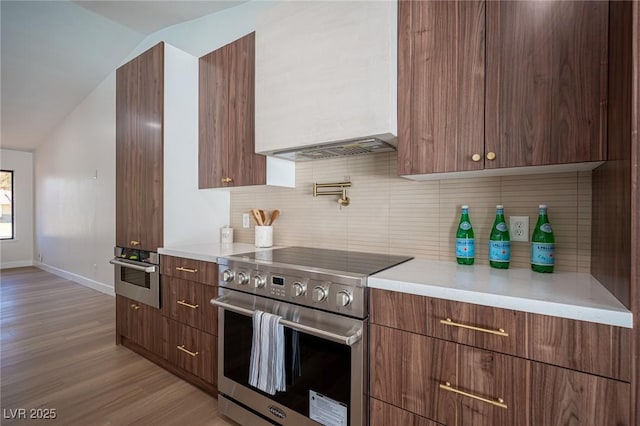4594 Cabo Ln, Las Vegas, NV 89121 - kitchen featuring stainless steel appliances, modern cabinets, light wood finished floors, light countertops, and vaulted ceiling
