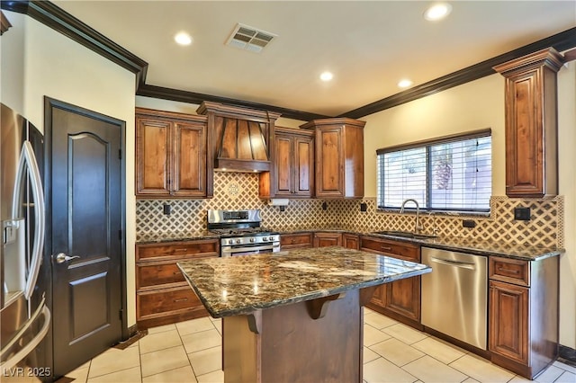 235 Calvino Ave, Las Vegas, NV 89183 - kitchen featuring appliances with stainless steel finishes, ornamental molding, a kitchen island, dark stone countertops, and light tile patterned floors