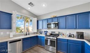 11018 Salernes St, Las Vegas, NV 89141 - kitchen with appliances with stainless steel finishes, vaulted ceiling, light countertops, blue cabinetry, and dark wood-type flooring