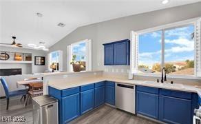 11018 Salernes St, Las Vegas, NV 89141 - kitchen with dishwasher, a peninsula, wood finished floors, blue cabinetry, and vaulted ceiling