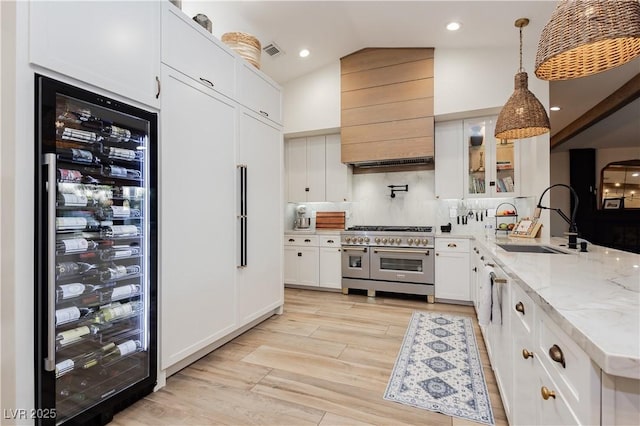 3227 Paintedhills Ave, Las Vegas, NV 89120 - kitchen featuring double oven range, custom range hood, beverage cooler, lofted ceiling, and light stone counters