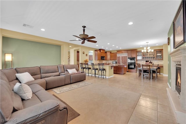 9516 Bluff Ledge Ave, Las Vegas, NV 89149 - living room featuring light tile patterned flooring, a chandelier, recessed lighting, a warm lit fireplace, and ceiling fan