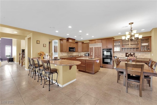 9516 Bluff Ledge Ave, Las Vegas, NV 89149 - kitchen featuring black appliances, a peninsula, tasteful backsplash, a breakfast bar, and a chandelier