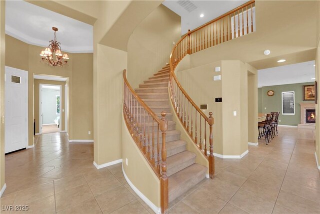 9516 Bluff Ledge Ave, Las Vegas, NV 89149 - staircase with tile patterned flooring, a high ceiling, a chandelier, recessed lighting, and a lit fireplace