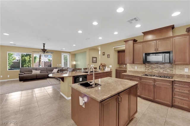 9516 Bluff Ledge Ave, Las Vegas, NV 89149 - kitchen featuring black microwave, stainless steel gas cooktop, a kitchen island with sink, open floor plan, and light tile patterned floors