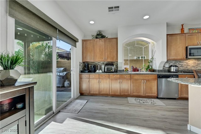 10167 Bishops Peak Ct, Las Vegas, NV 89141 - kitchen featuring stainless steel appliances, light wood-style floors, stone counters, backsplash, and recessed lighting