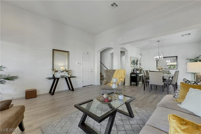 10167 Bishops Peak Ct, Las Vegas, NV 89141 - living area featuring arched walkways, light wood-style floors, a chandelier, and stairs