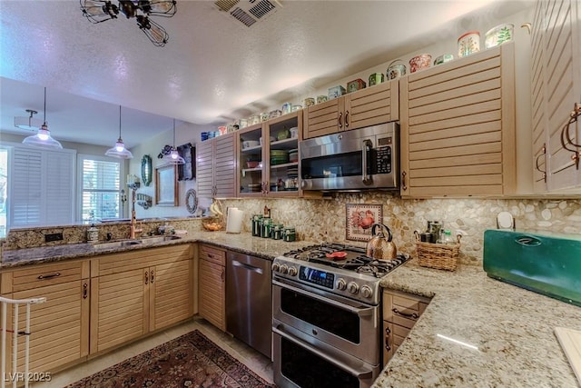 5046 Crooked Stick Way, Las Vegas, NV 89113 - kitchen with appliances with stainless steel finishes, backsplash, glass insert cabinets, light stone countertops, and a peninsula