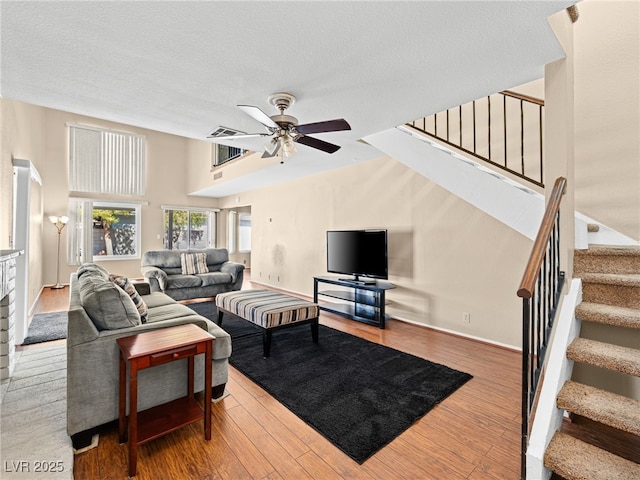 3740 Broadriver Dr, Las Vegas, NV 89108 - living area featuring a ceiling fan, stairs, wood finished floors, a textured ceiling, and a towering ceiling