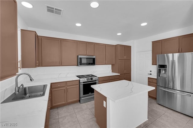 11010 Santorini Dr, Las Vegas, NV 89141 - kitchen with appliances with stainless steel finishes, a kitchen island, light stone counters, recessed lighting, and light tile patterned flooring