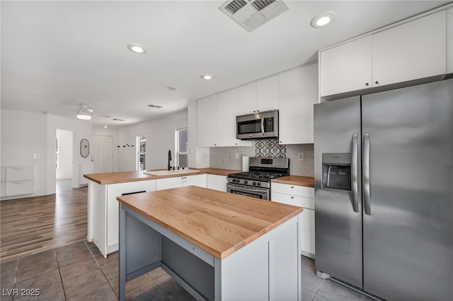 4020 Pistachio Nut Ave, Las Vegas, NV 89115 - kitchen featuring stainless steel appliances, wooden counters, a peninsula, white cabinets, and tasteful backsplash