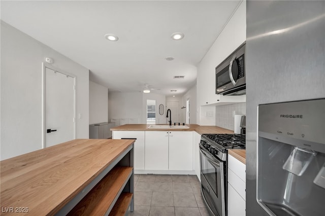 4020 Pistachio Nut Ave, Las Vegas, NV 89115 - kitchen featuring appliances with stainless steel finishes, butcher block counters, white cabinets, light tile patterned flooring, and a peninsula