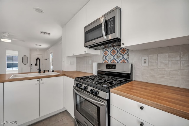 4020 Pistachio Nut Ave, Las Vegas, NV 89115 - kitchen featuring stainless steel appliances, wood counters, white cabinets, tasteful backsplash, and light tile patterned floors