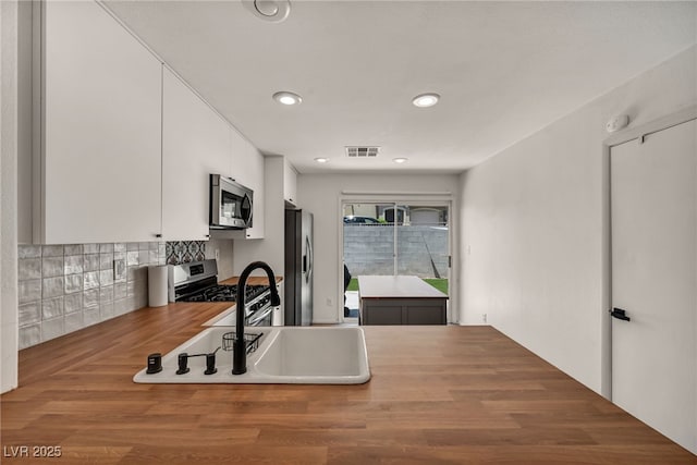 4020 Pistachio Nut Ave, Las Vegas, NV 89115 - kitchen featuring appliances with stainless steel finishes, white cabinets, decorative backsplash, recessed lighting, and wood finished floors