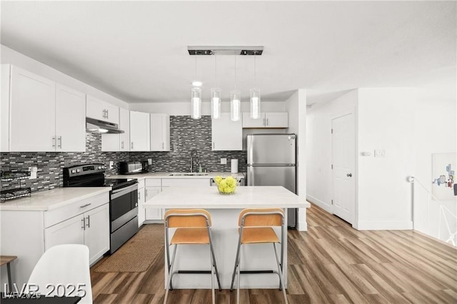 3208 Alcoa Ave, Las Vegas, NV 89102 - kitchen with appliances with stainless steel finishes, under cabinet range hood, wood finished floors, and tasteful backsplash