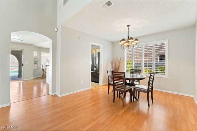 1337 Maplegrove Cir, Las Vegas, NV 89108 - dining area with arched walkways, light wood finished floors, a chandelier, and a textured ceiling