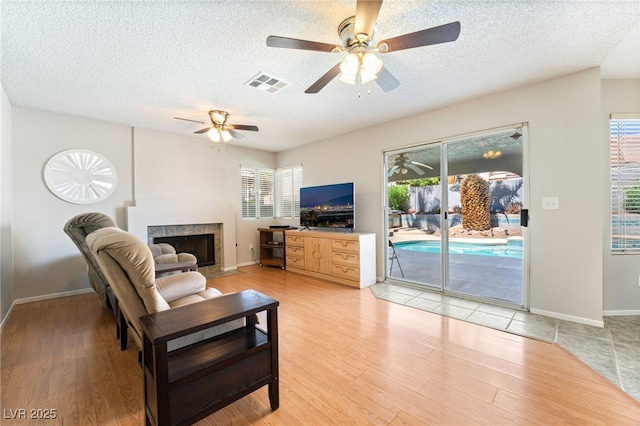1337 Maplegrove Cir, Las Vegas, NV 89108 - living room featuring a textured ceiling, ceiling fan, a fireplace, and light wood-style flooring