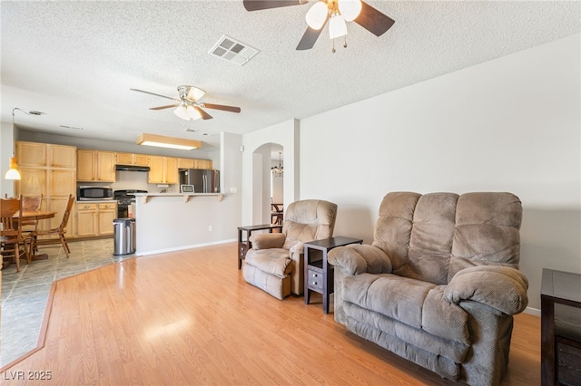 1337 Maplegrove Cir, Las Vegas, NV 89108 - living area featuring ceiling fan, arched walkways, light wood-style floors, and a textured ceiling