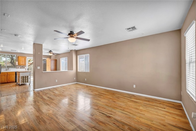 8557 Hidden Pines Ave, Las Vegas, NV 89143 - unfurnished living room featuring light wood-style flooring, a ceiling fan, and a textured ceiling