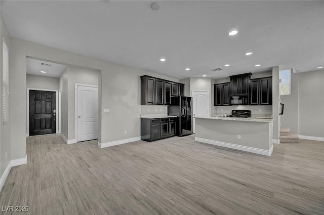 6373 Beavertail Pond Ave, Las Vegas, NV 89122 - kitchen with black appliances, light countertops, light wood-style floors, dark cabinets, and open floor plan
