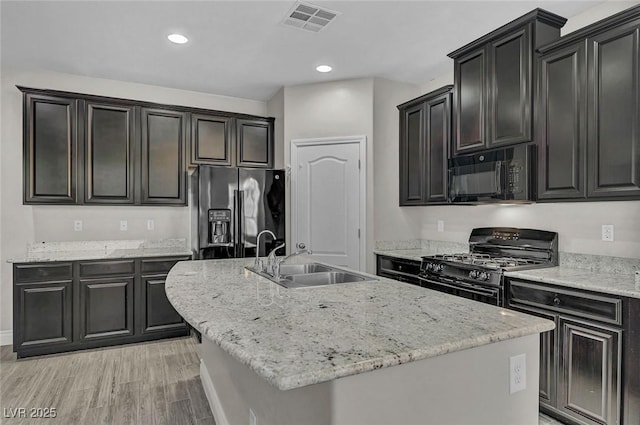 6373 Beavertail Pond Ave, Las Vegas, NV 89122 - kitchen with black appliances, an island with sink, light wood finished floors, recessed lighting, and light stone counters
