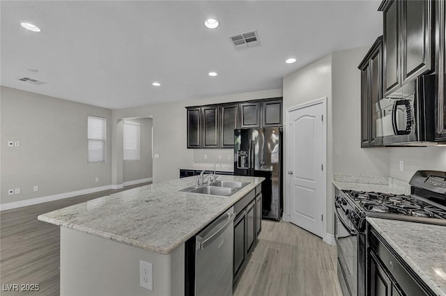 6373 Beavertail Pond Ave, Las Vegas, NV 89122 - kitchen with black appliances, light wood-style floors, recessed lighting, an island with sink, and light stone counters