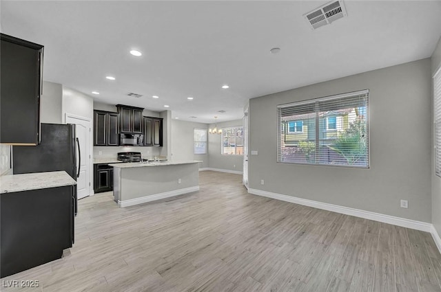 6373 Beavertail Pond Ave, Las Vegas, NV 89122 - kitchen with black microwave, range, a chandelier, light wood-style floors, and recessed lighting