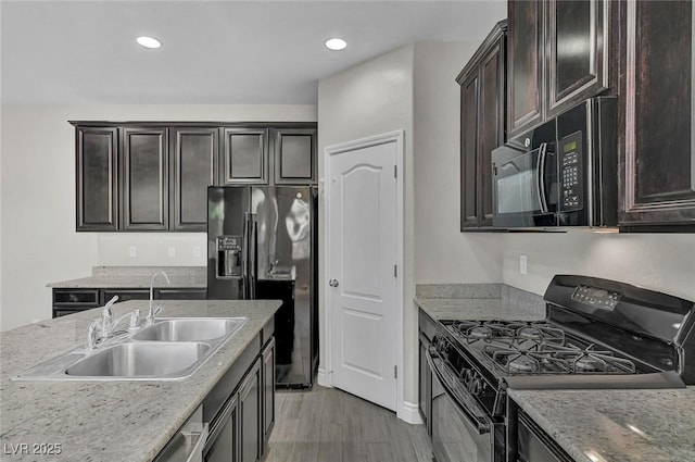 6373 Beavertail Pond Ave, Las Vegas, NV 89122 - kitchen with black appliances, dark brown cabinetry, light wood-style flooring, recessed lighting, and light stone countertops