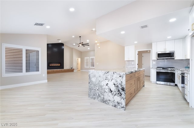 8904 Marble Dr, Las Vegas, NV 89134 - kitchen with appliances with stainless steel finishes, ceiling fan, light wood-style floors, tasteful backsplash, and vaulted ceiling