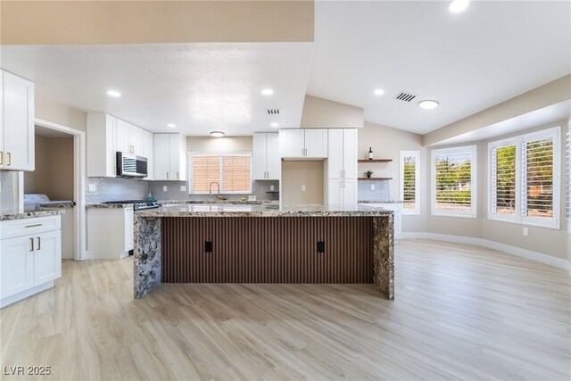 8904 Marble Dr, Las Vegas, NV 89134 - kitchen with stainless steel microwave, light wood-type flooring, a center island, plenty of natural light, and vaulted ceiling