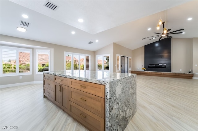 8904 Marble Dr, Las Vegas, NV 89134 - kitchen featuring vaulted ceiling, light wood-type flooring, a center island, recessed lighting, and light stone countertops