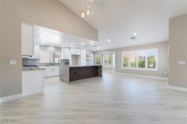 8904 Marble Dr, Las Vegas, NV 89134 - kitchen with open floor plan, light wood finished floors, white cabinetry, a kitchen island, and decorative backsplash