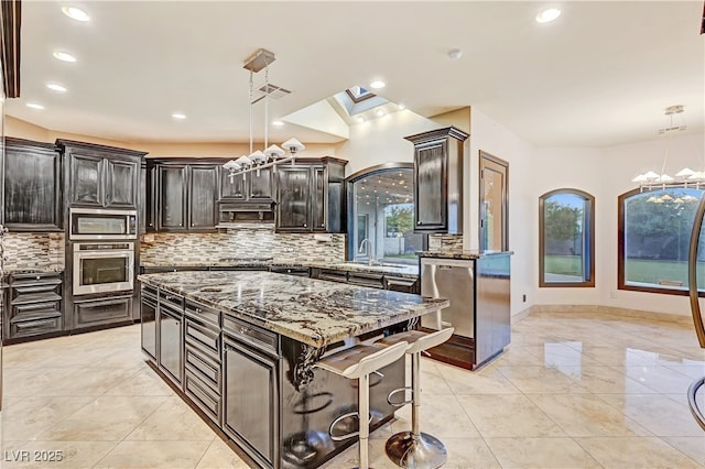 7751 Radcliff St, Las Vegas, NV 89123 - kitchen featuring stainless steel appliances, stone counters, tasteful backsplash, a center island, and recessed lighting