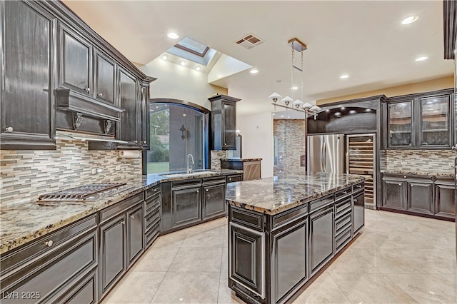 7751 Radcliff St, Las Vegas, NV 89123 - kitchen with appliances with stainless steel finishes, backsplash, a skylight, light stone countertops, and a center island