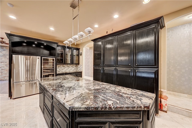 7751 Radcliff St, Las Vegas, NV 89123 - kitchen with arched walkways, freestanding refrigerator, dark cabinets, dark stone counters, and tasteful backsplash