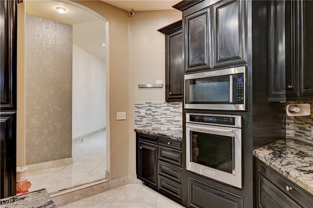 7751 Radcliff St, Las Vegas, NV 89123 - kitchen with appliances with stainless steel finishes, arched walkways, tasteful backsplash, and light stone counters