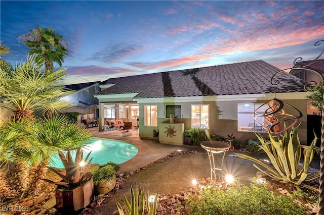 216 Chestnut Ridge Cir, Henderson, NV 89012 - back of property at dusk with stucco siding, a patio, and an outdoor pool