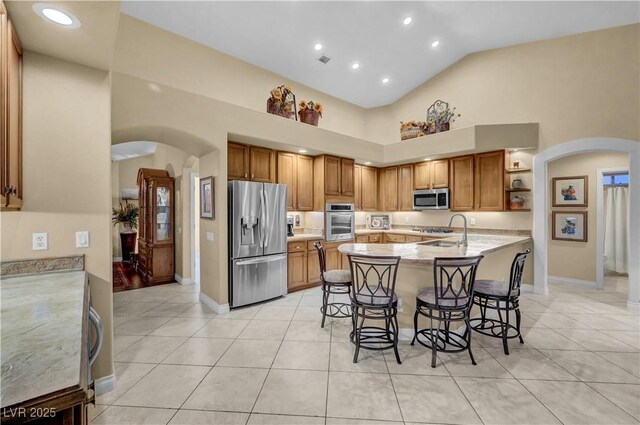 216 Chestnut Ridge Cir, Henderson, NV 89012 - kitchen featuring appliances with stainless steel finishes, arched walkways, open shelves, a breakfast bar area, and light tile patterned floors