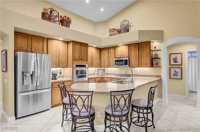 216 Chestnut Ridge Cir, Henderson, NV 89012 - kitchen featuring appliances with stainless steel finishes, arched walkways, light tile patterned floors, light countertops, and a high ceiling