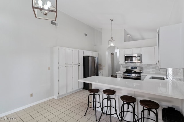 5621 Desert Creek Way, Las Vegas, NV 89149 - kitchen featuring appliances with stainless steel finishes, a peninsula, tasteful backsplash, high vaulted ceiling, and light countertops