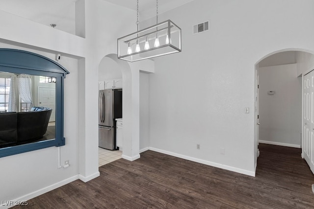 5621 Desert Creek Way, Las Vegas, NV 89149 - unfurnished living room with arched walkways, a high ceiling, and wood finished floors