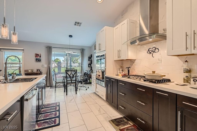 5021 Cliffrose Dr, Las Vegas, NV 89130 - kitchen with wall chimney range hood, stainless steel appliances, light countertops, white cabinetry, and light marble finish flooring