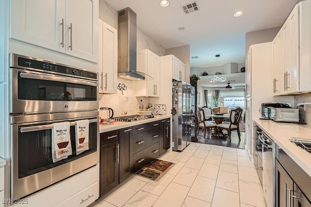 5021 Cliffrose Dr, Las Vegas, NV 89130 - kitchen featuring stainless steel appliances, wall chimney exhaust hood, light countertops, tasteful backsplash, and white cabinetry