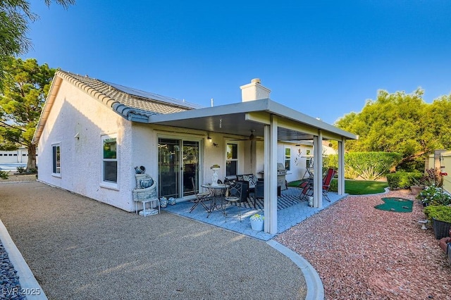 5021 Cliffrose Dr, Las Vegas, NV 89130 - back of house featuring roof mounted solar panels, a patio, a chimney, stucco siding, and ceiling fan
