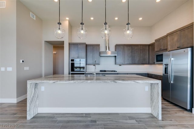 4152 Yucca Bloom St Unit 1, Las Vegas, NV 89135 - kitchen featuring appliances with stainless steel finishes, a large island, light stone counters, dark brown cabinets, and decorative backsplash