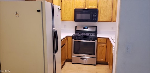 1128 Dusty Creek St, Las Vegas, NV 89128 - kitchen with freestanding refrigerator, black microwave, gas stove, light countertops, and light wood-style floors