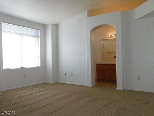 1128 Dusty Creek St, Las Vegas, NV 89128 - empty room featuring light colored carpet, arched walkways, and healthy amount of natural light