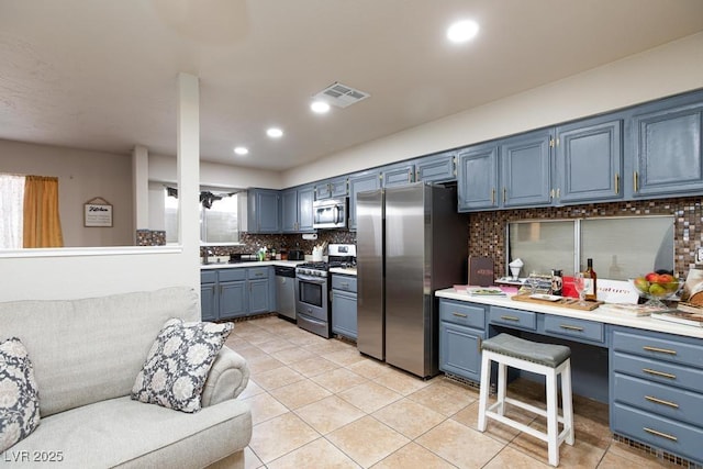 2912 Drury St, Las Vegas, NV 89108 - kitchen with stainless steel appliances, backsplash, light tile patterned floors, blue cabinetry, and light countertops