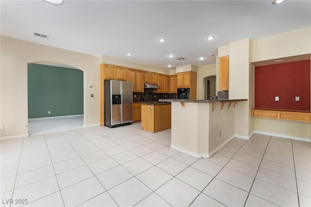 8901 Goldstone Ave, Las Vegas, NV 89143 - kitchen with stainless steel fridge with ice dispenser, under cabinet range hood, a breakfast bar area, arched walkways, and recessed lighting