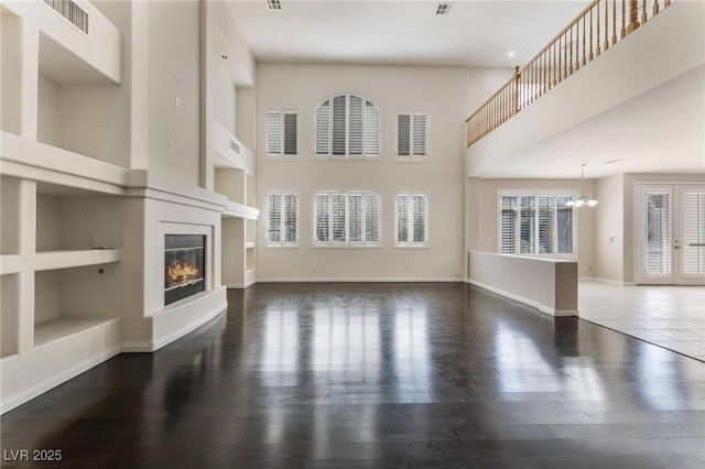 8901 Goldstone Ave, Las Vegas, NV 89143 - unfurnished living room featuring built in shelves, a chandelier, a fireplace, wood finished floors, and a high ceiling